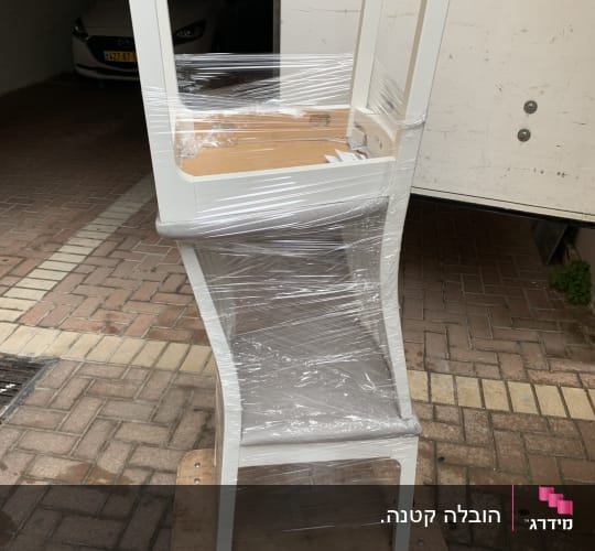 כיסא עטוף בניילון על משטח עץ